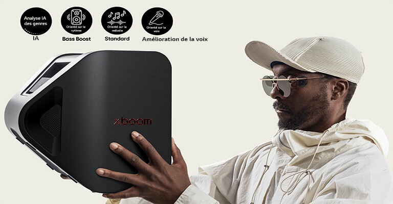 will.i.am en tenue blanche et casquette blanche tient la xboom Stage 301 avec ses deux mains devant son visage.