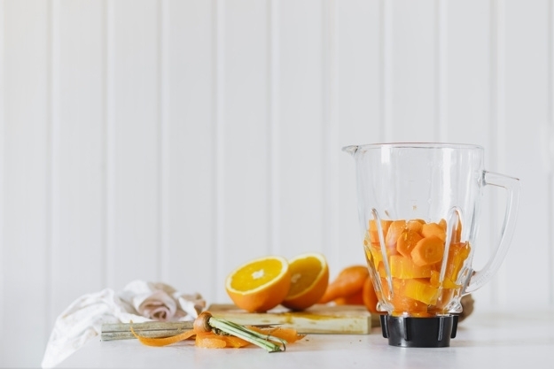 Blender avec des fruits coupÃ©s prÃ¨s d'orange